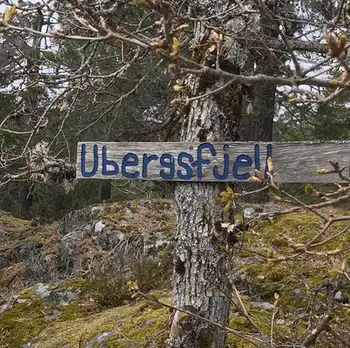 A sign in the woods with the word "ubergsfjell" written on it.
