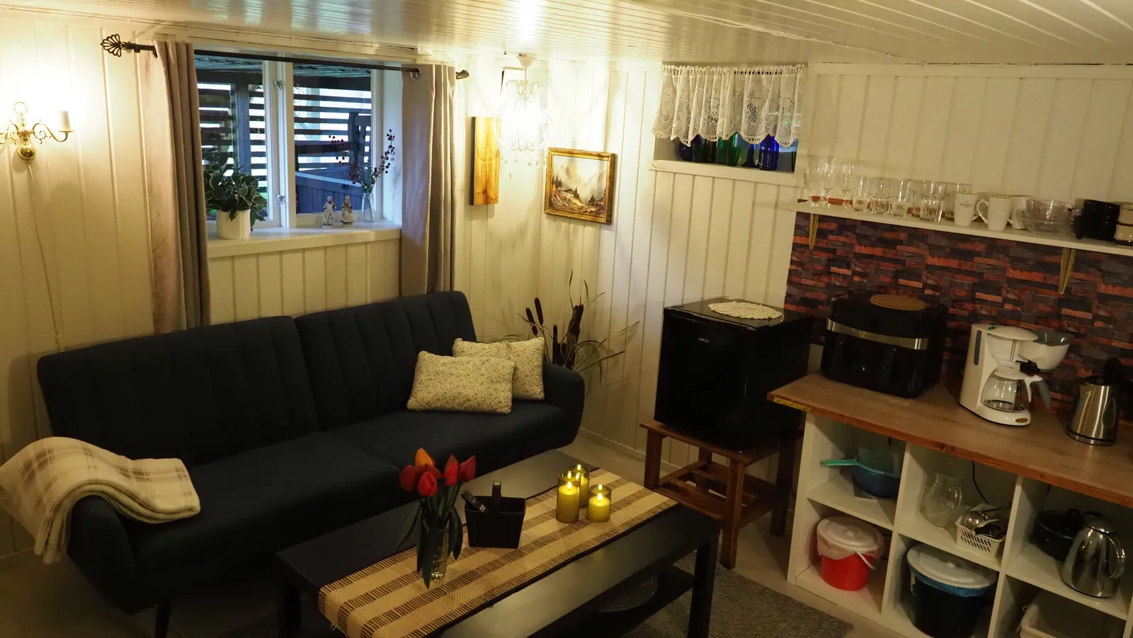 Warm cabin interior with sofa, table, and kitchenette at Riverside Bliss
