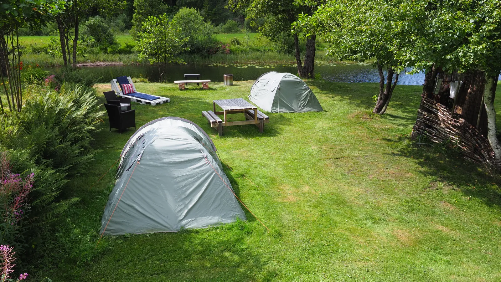 Riverside Bliss lawn with tents, chairs, and calm water nearby