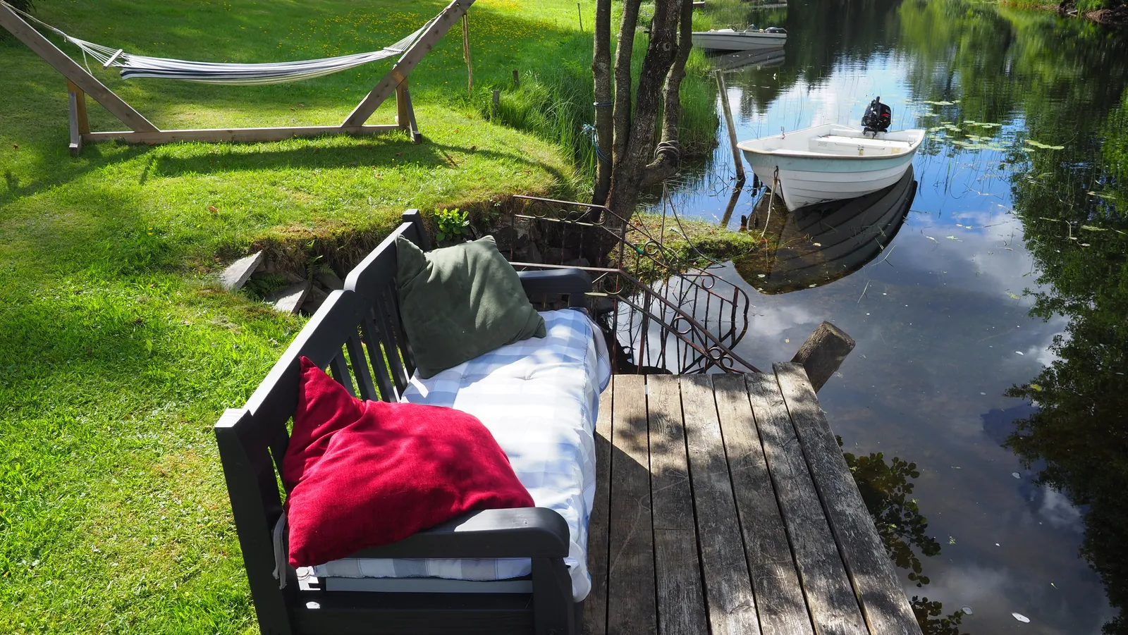 Cushioned dock seating and hammock beside still water at Riverside Bliss