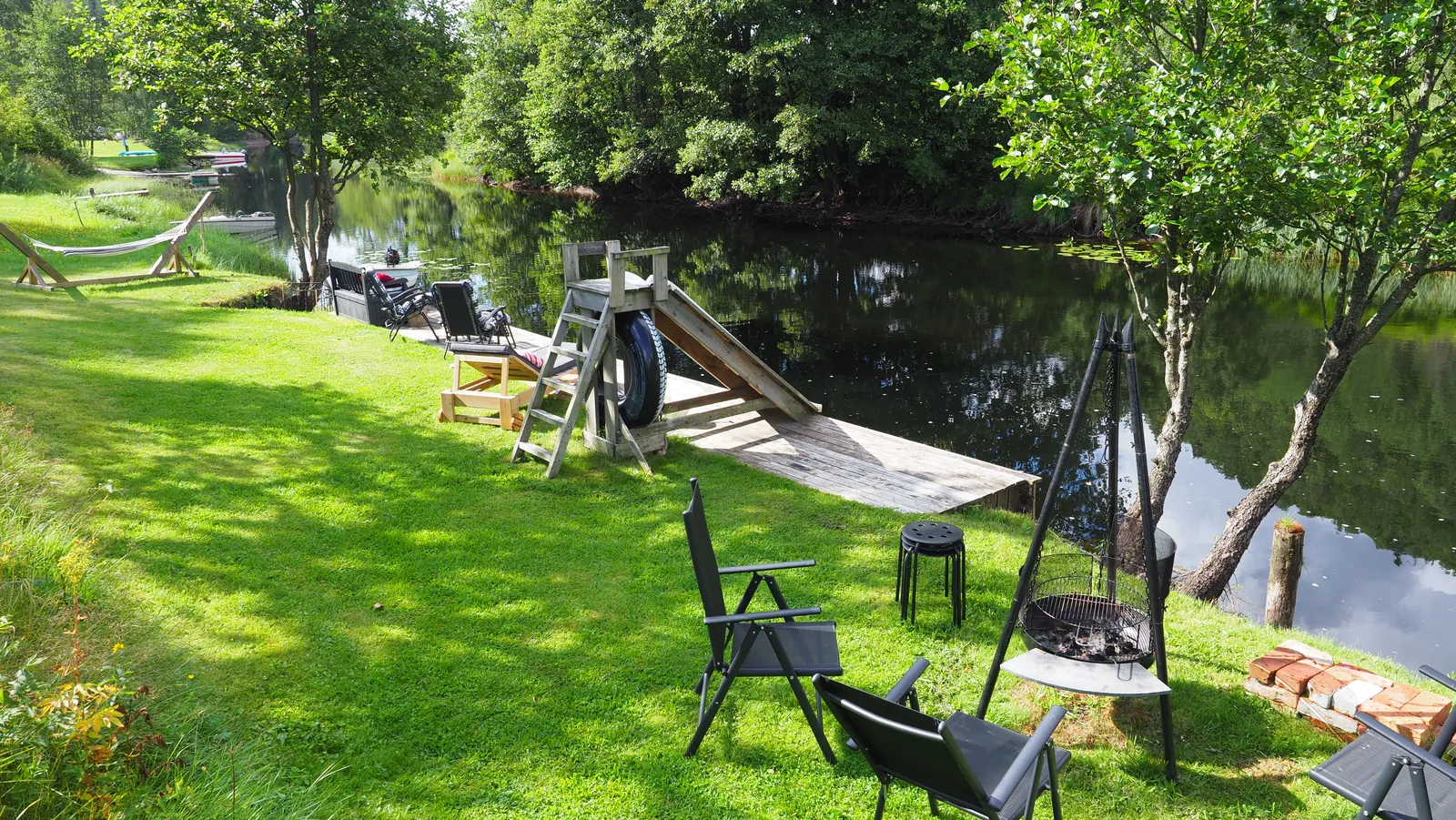 Riverside Bliss lawn with chairs, hammock, and wooden dock