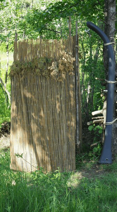 A quaint outdoor gas-heated shower, evoking "Bali style" charm, offers a relaxing retreat in a lush, natural setting